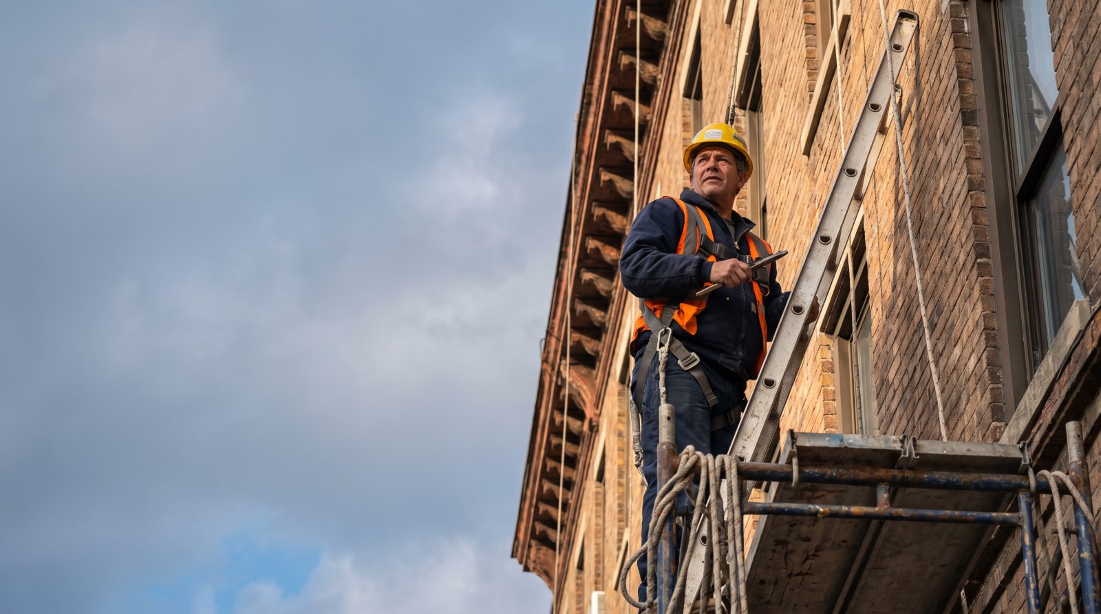 Worker harnessed on scaffolding high on a building exterior